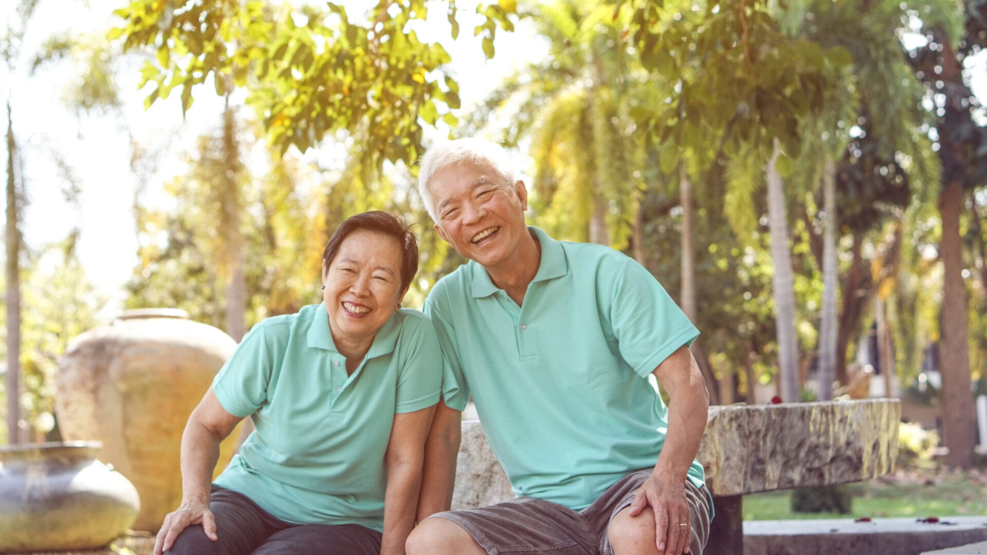 Happy Asian elderly couple laugh together in green natural park